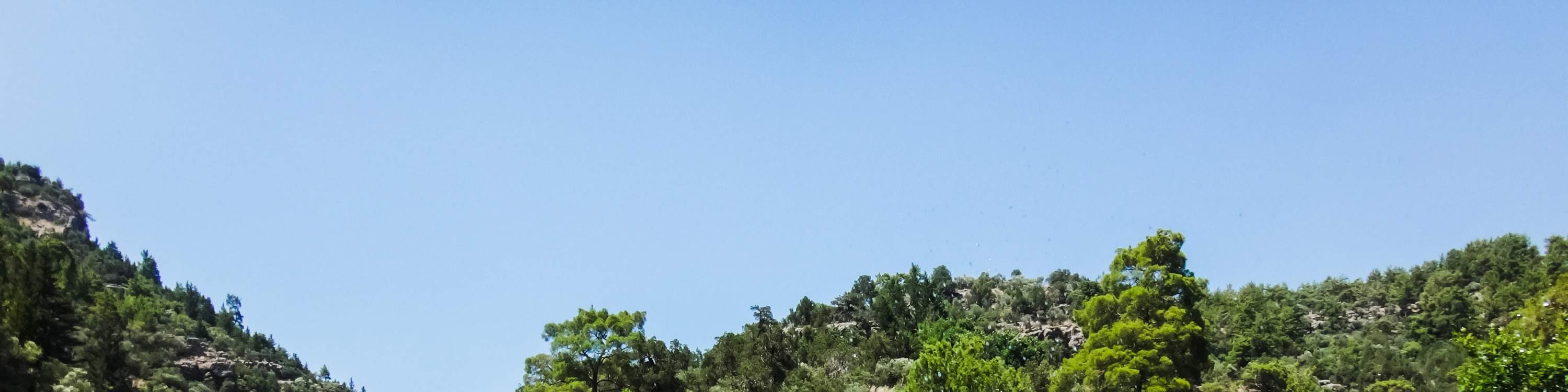 orang ramai melakukan aktiviti *water rafting* di hadapan bukit kecil
