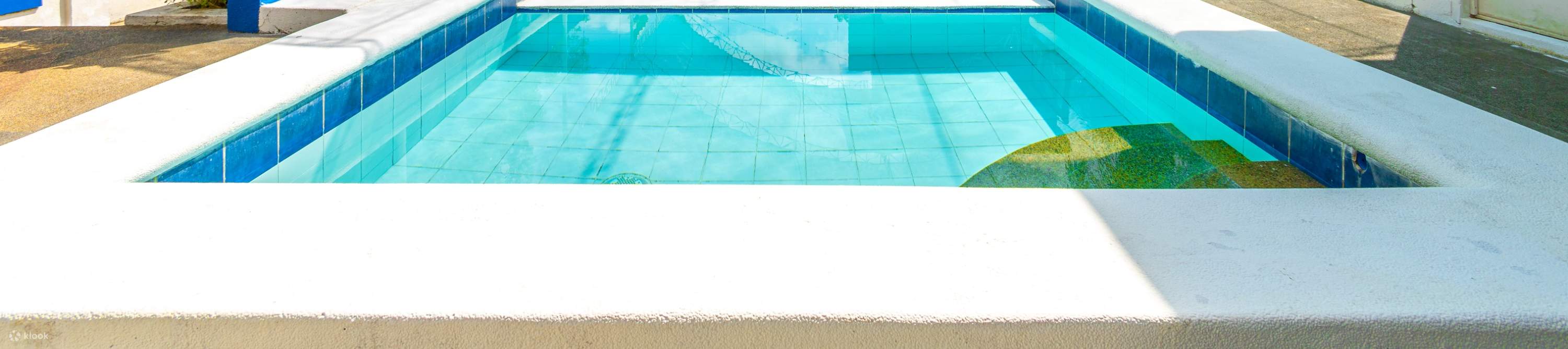 Una piscina serena con un tetto blu, circondata da piastrelle blu e bianche