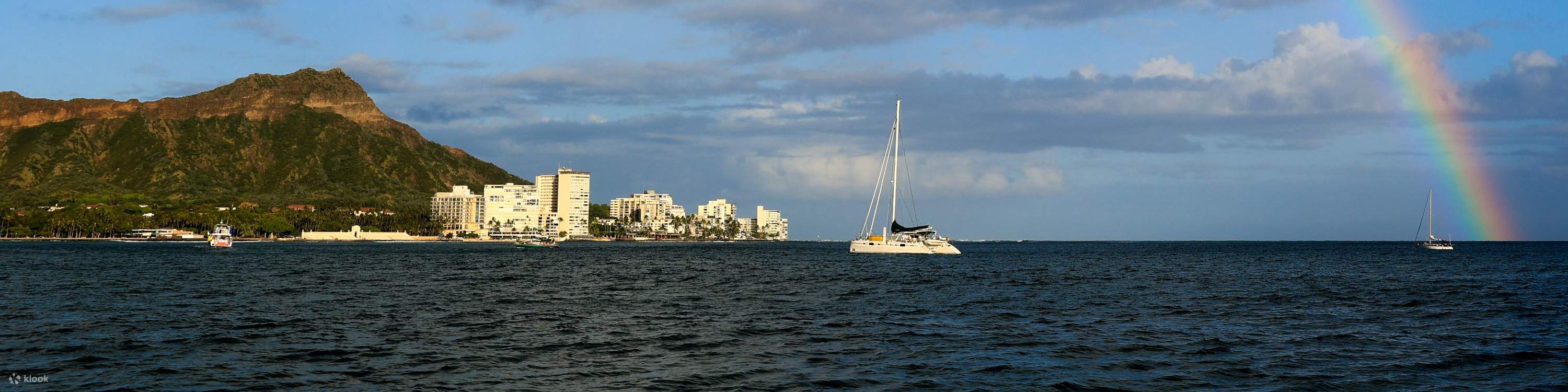 Яркая радуга простирается по небу, а под ней плывет лодка.