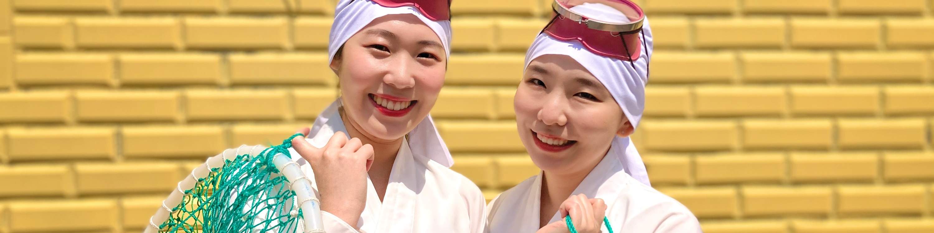 Những người phụ nữ mặc trang phục Haenyeo cầm dụng cụ đánh bắt cá