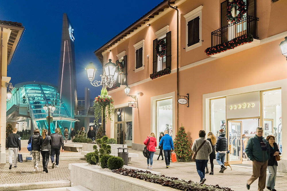 turisti e residenti che passeggiano nel centro commerciale in stile villaggio