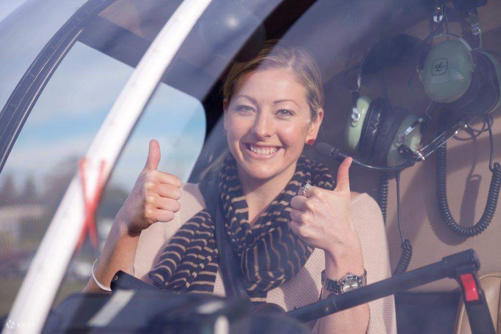 a woman with 2 thumbs up inside a helicopter