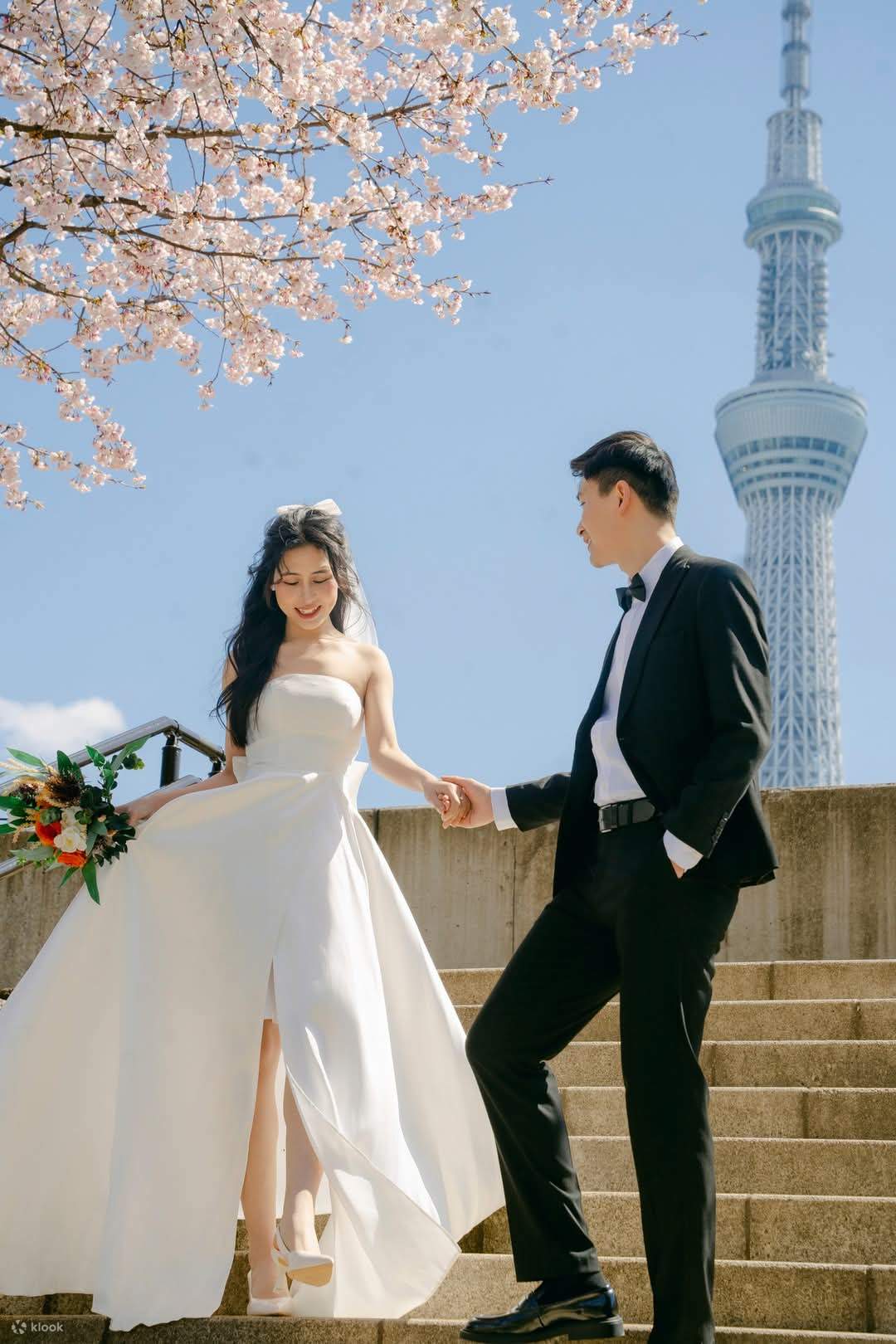 A photo shoot of a beautiful wedding dress with the Sky Tree and cherry blossoms in the background.