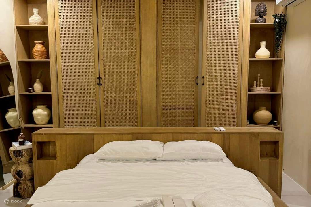 tempat tidur nyaman dengan seprai putih bersih dan lemari kayu bergaya pedesaan dengan rak