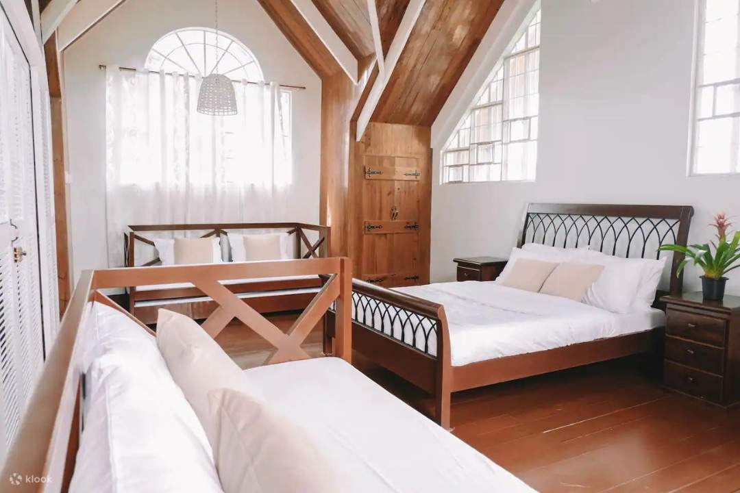 Habitación sencilla con sofá, dos camas y una ventana que permite la entrada de luz natural