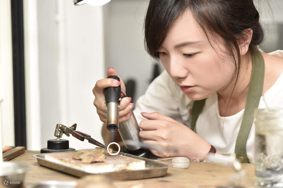 Une personne fabrique des bijoux en argent avec soin.