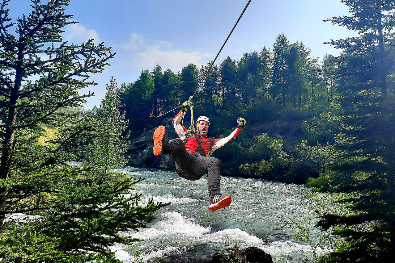 Un uomo con una maglietta rossa sta facendo zipline attraverso il fiume
