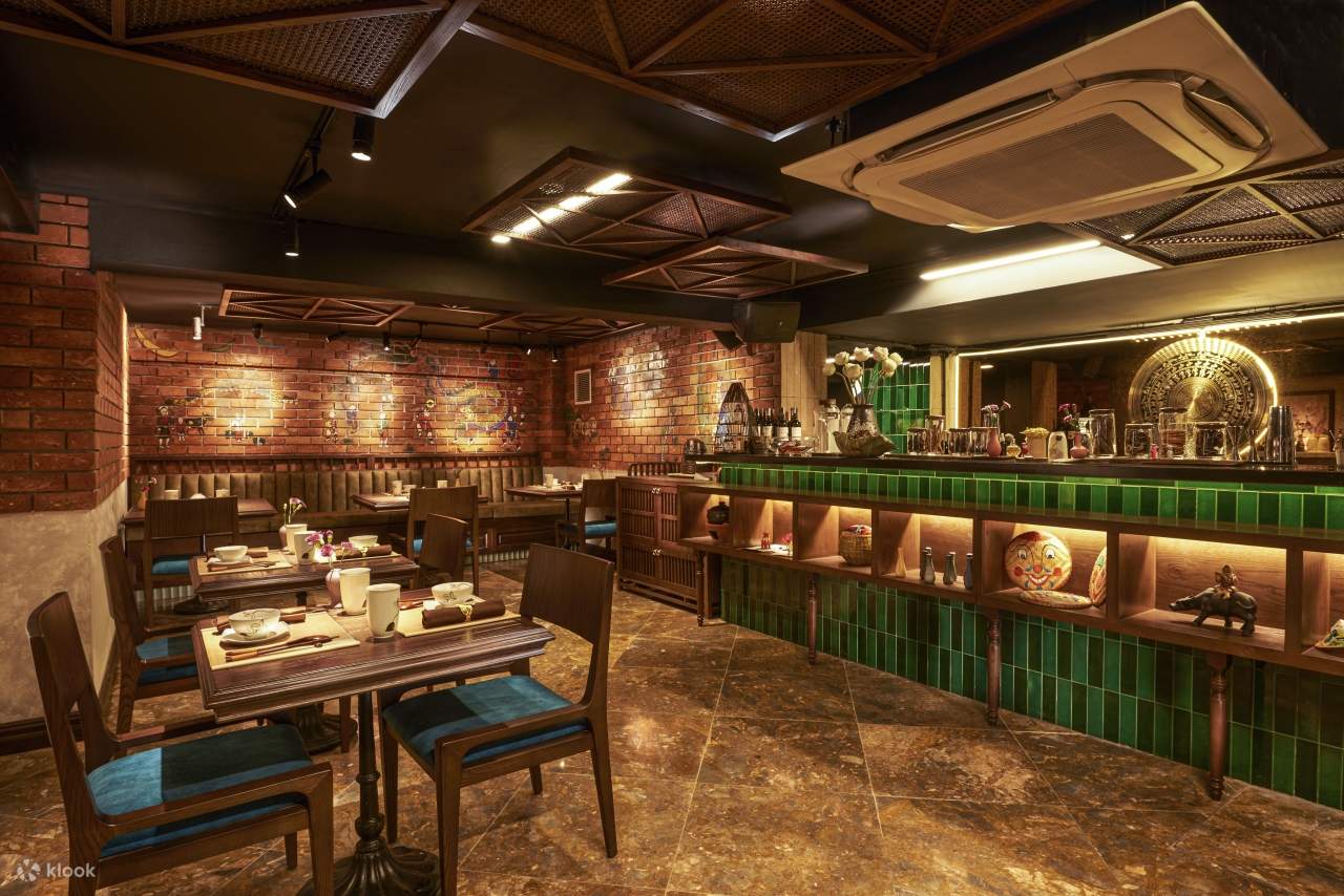 Một nhà hàng có tường gạch và quầy bar màu xanh lá cây, tạo nên một không gian ấm cúng và mộc mạc