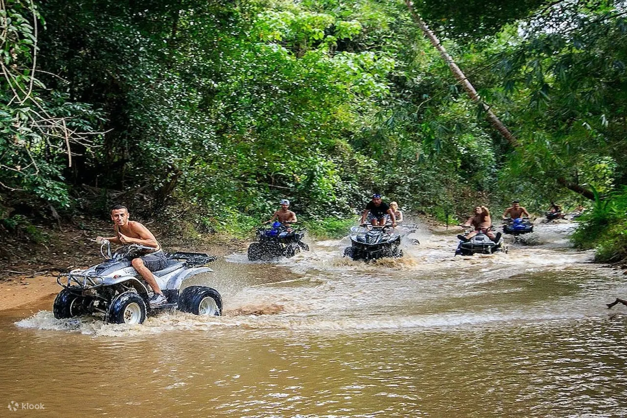 ATV 骑手飞溅穿过沼泽