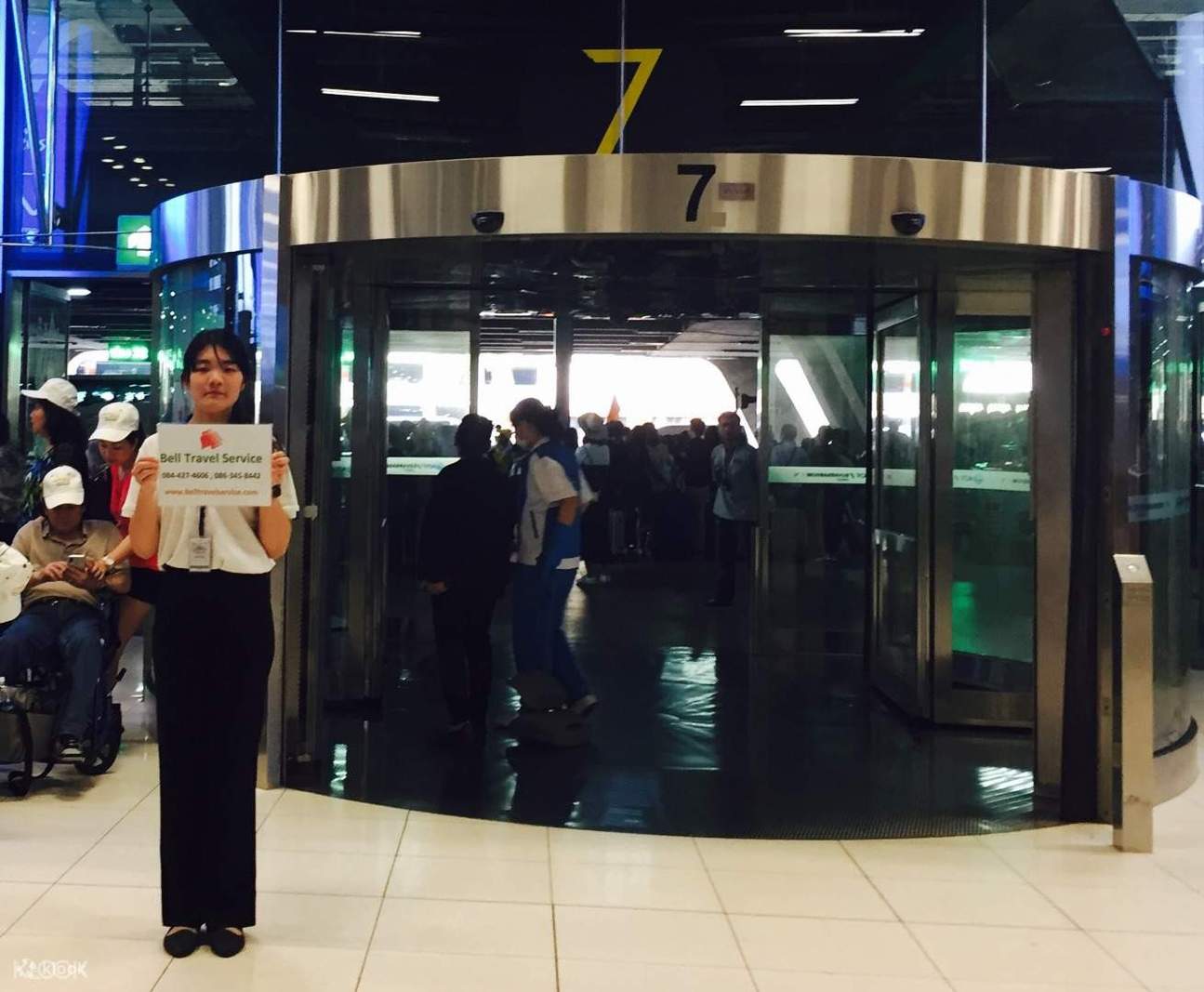 A Staff Holding Bell Travel Service Sign at BKK Airport