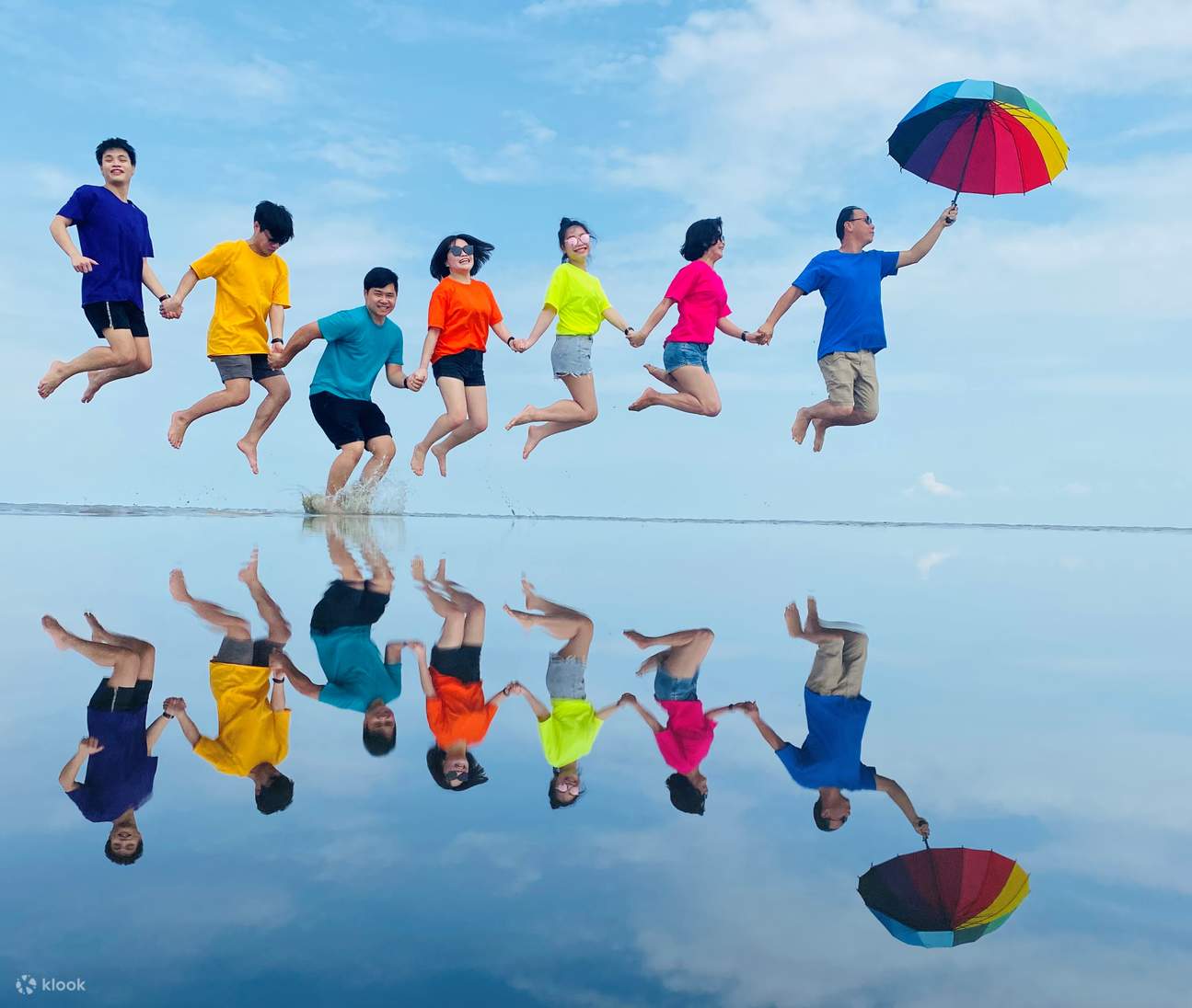 Gruppo di amiche che fanno un salto creativo con un ombrello arcobaleno