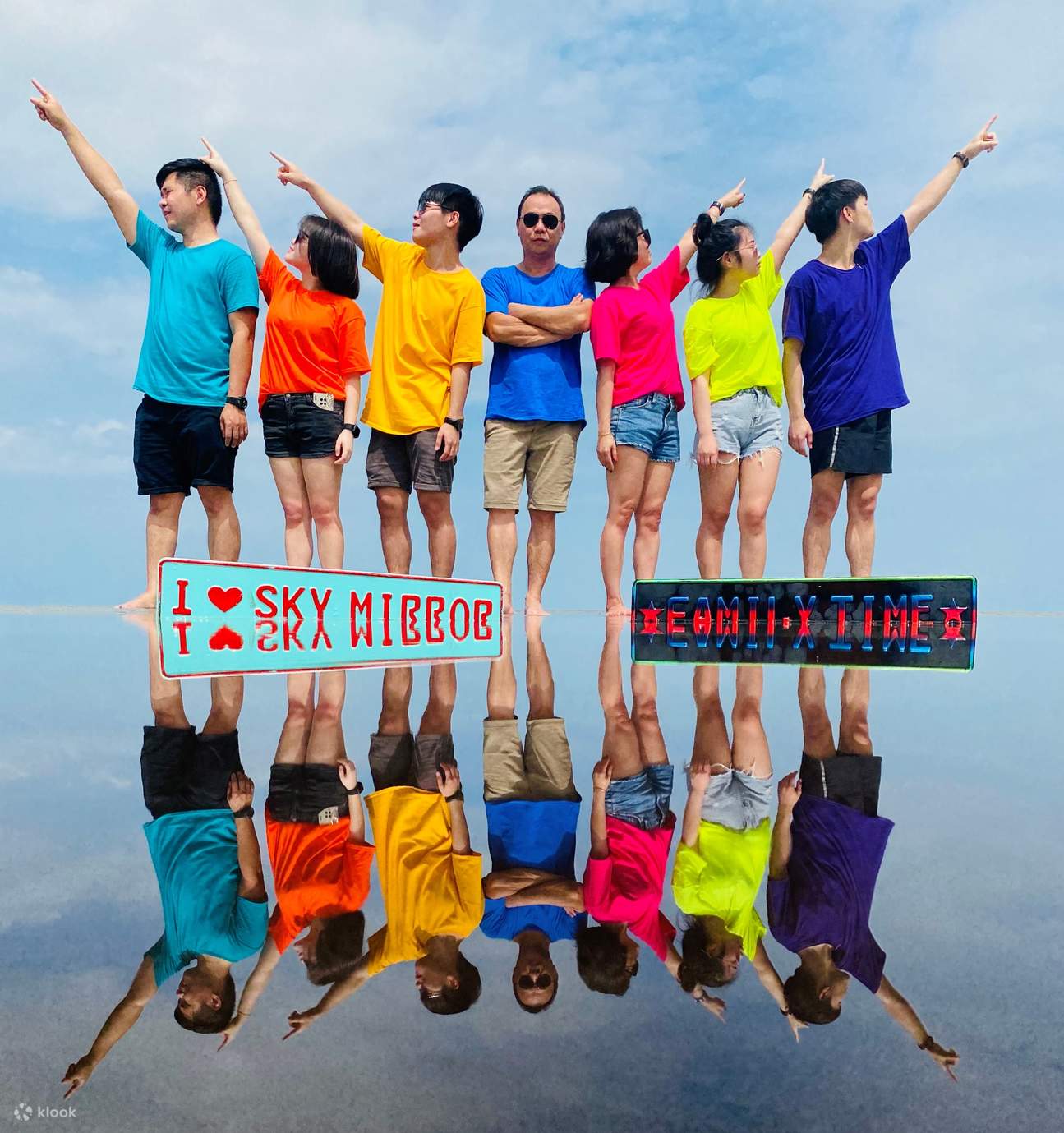 Pelawat memegang payung warna pelangi sambil bergambar di Pantai Sasaran, Kuala Selangor