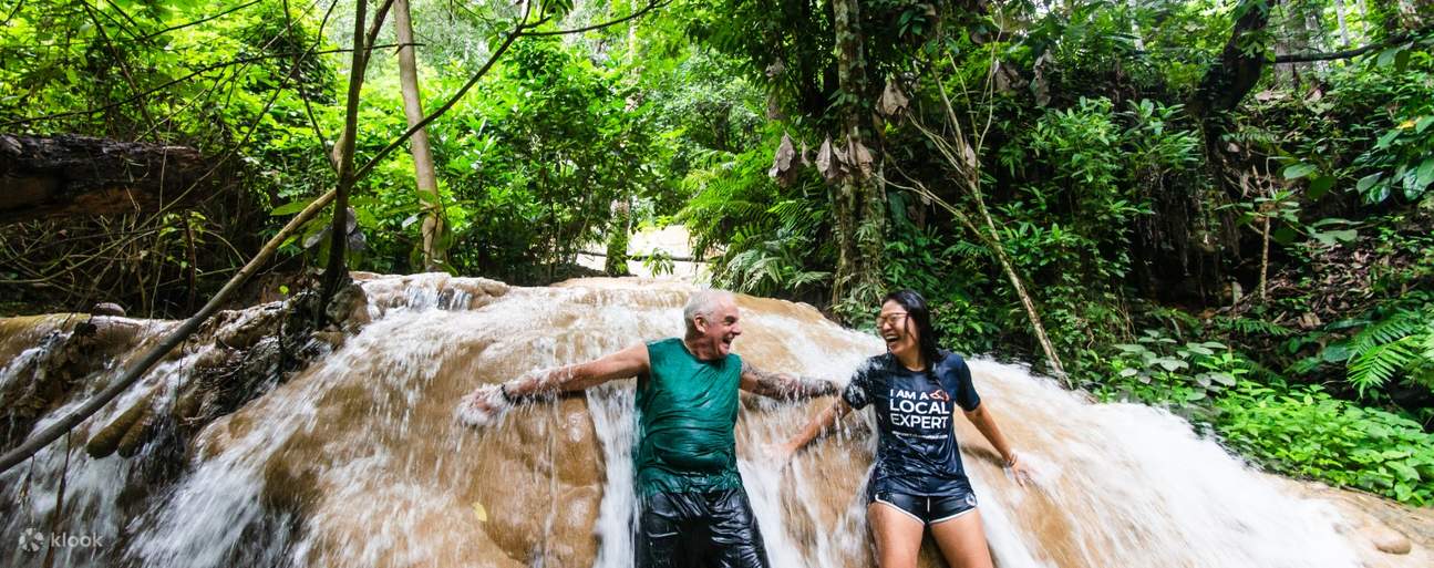 Hombre y mujer apoyados en roca caliza en las cascadas Sticky de Chiang Mai