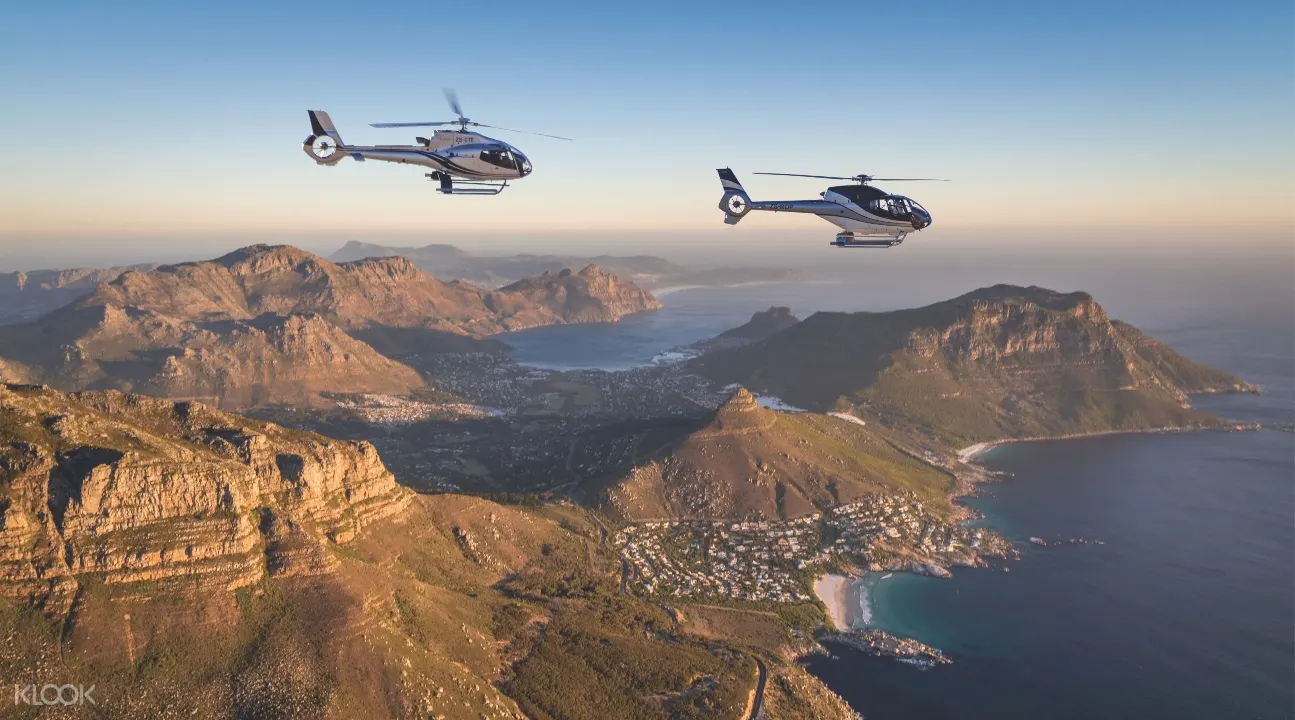 two helicopters flying above Cape Town during the late afternoon; there's a view of the mountains