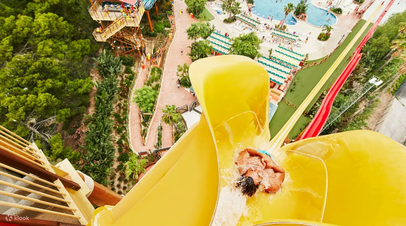 在 PortAventura Caribe 水上公园滑下黄色滑梯的人