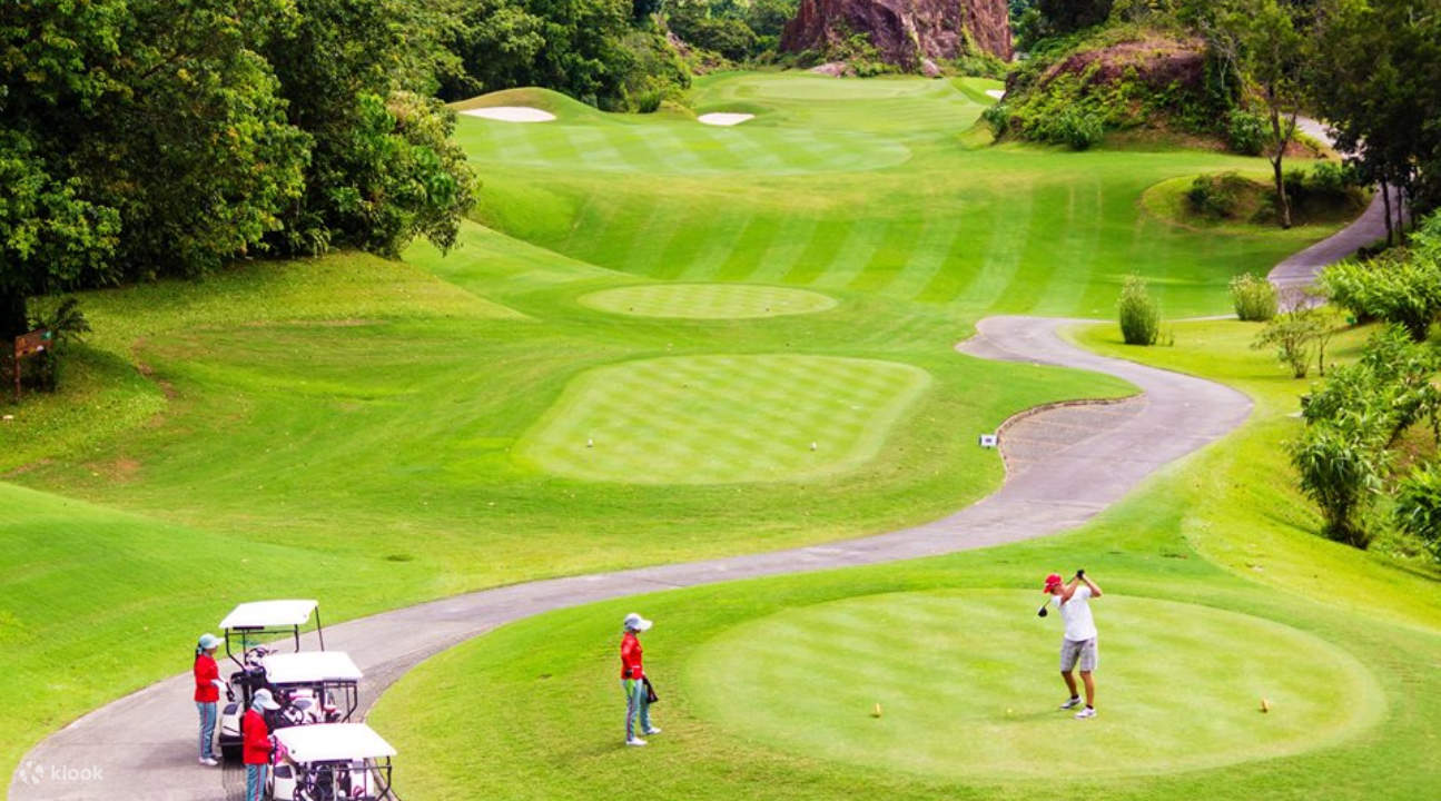 a golfer with caddies and golf carts somewhere in the Red Mountain Golf Club