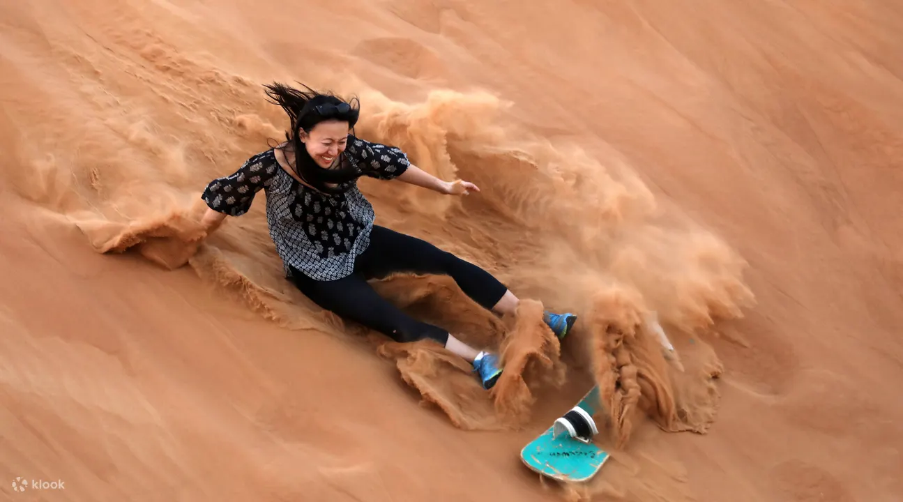 Một người phụ nữ trượt cát xuống cồn cát