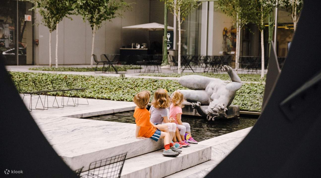 kids sitting on steps in the garden of moma