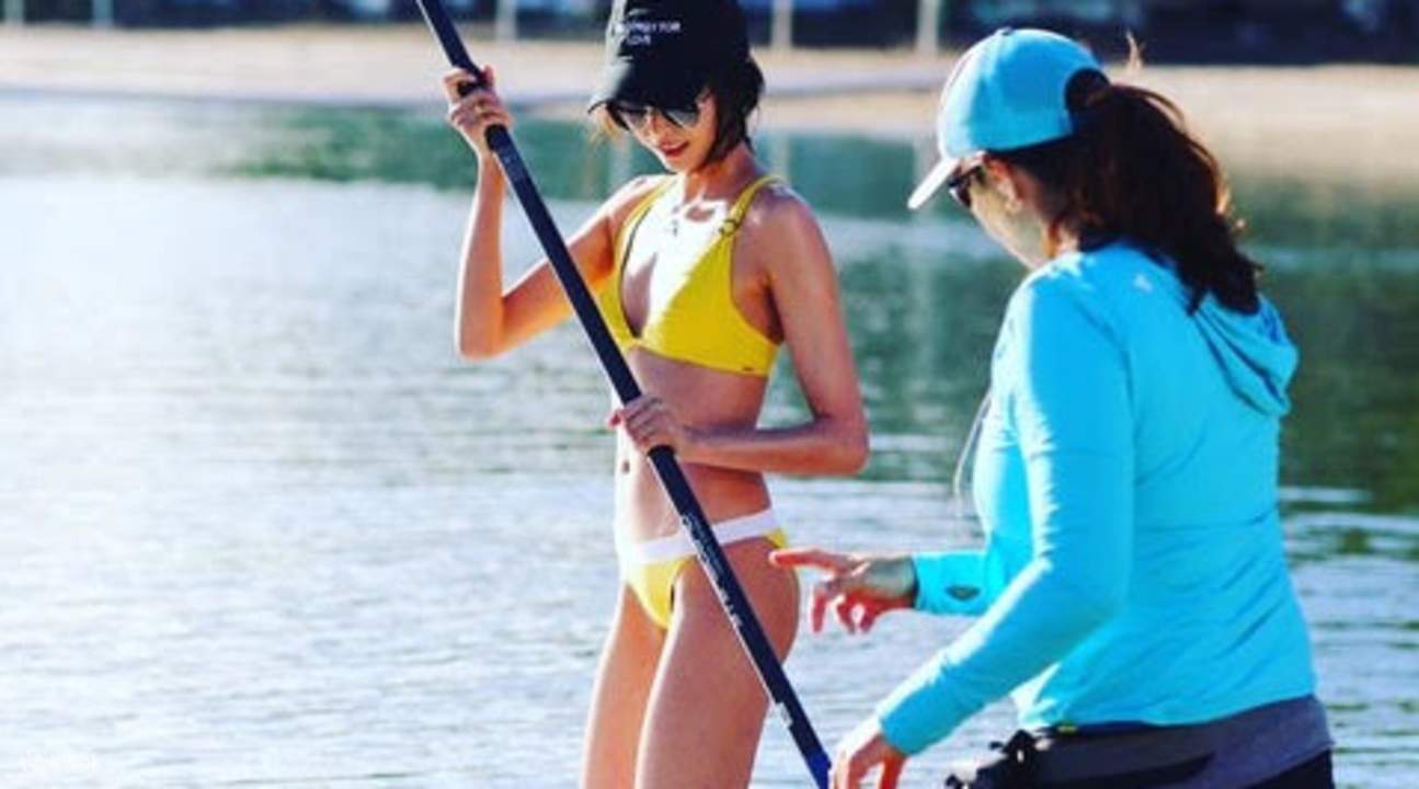 a guide teaching a girl how to SUP