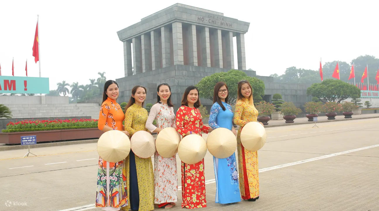 在胡志明陵墓附近，身着长袍、头戴锥形帽的妇女