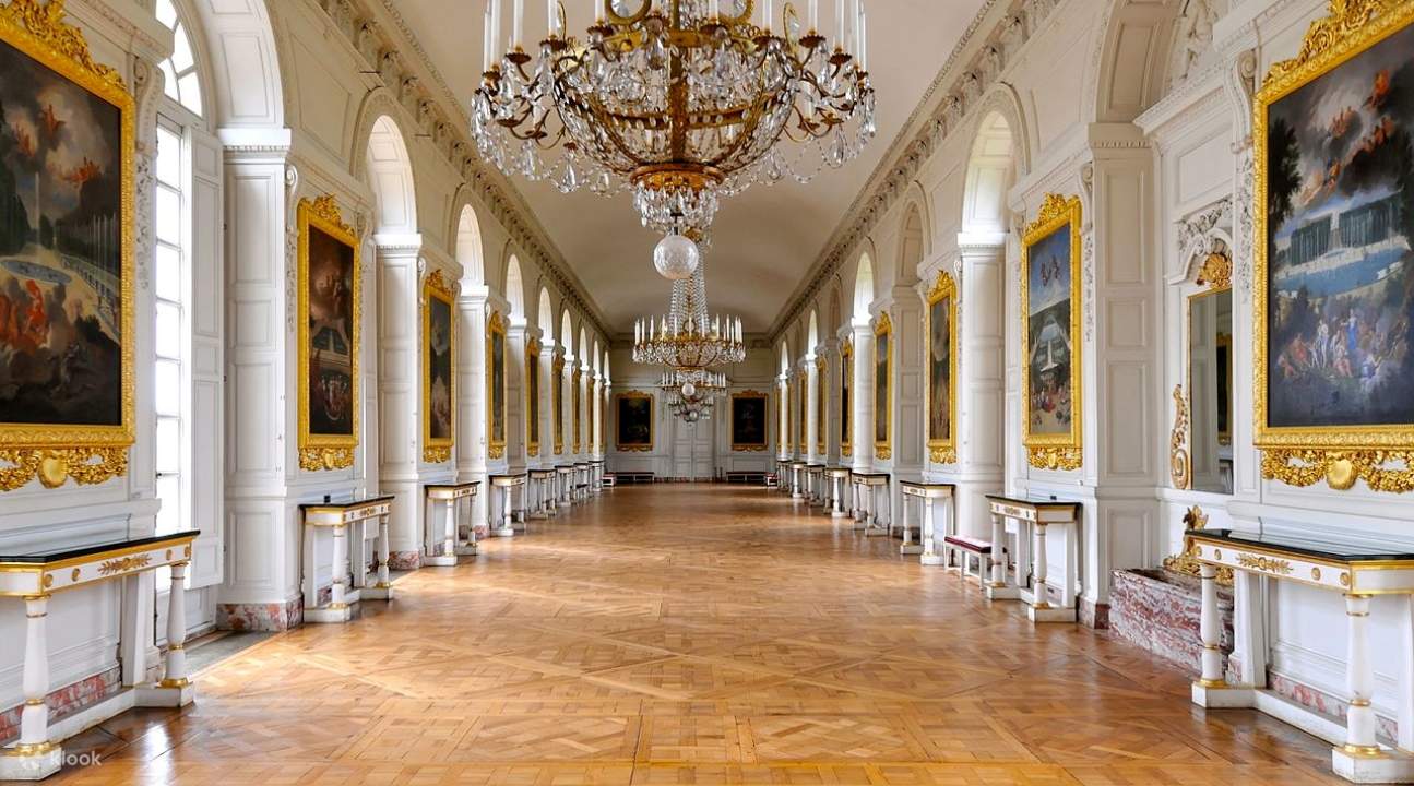 a hall inside Versailles; there are paintings on the side