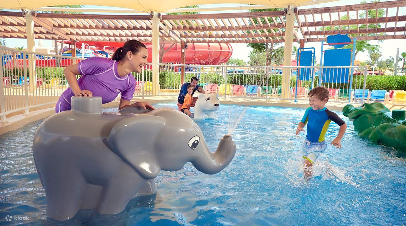 mother and child playing in with elephant fountain in a pool
