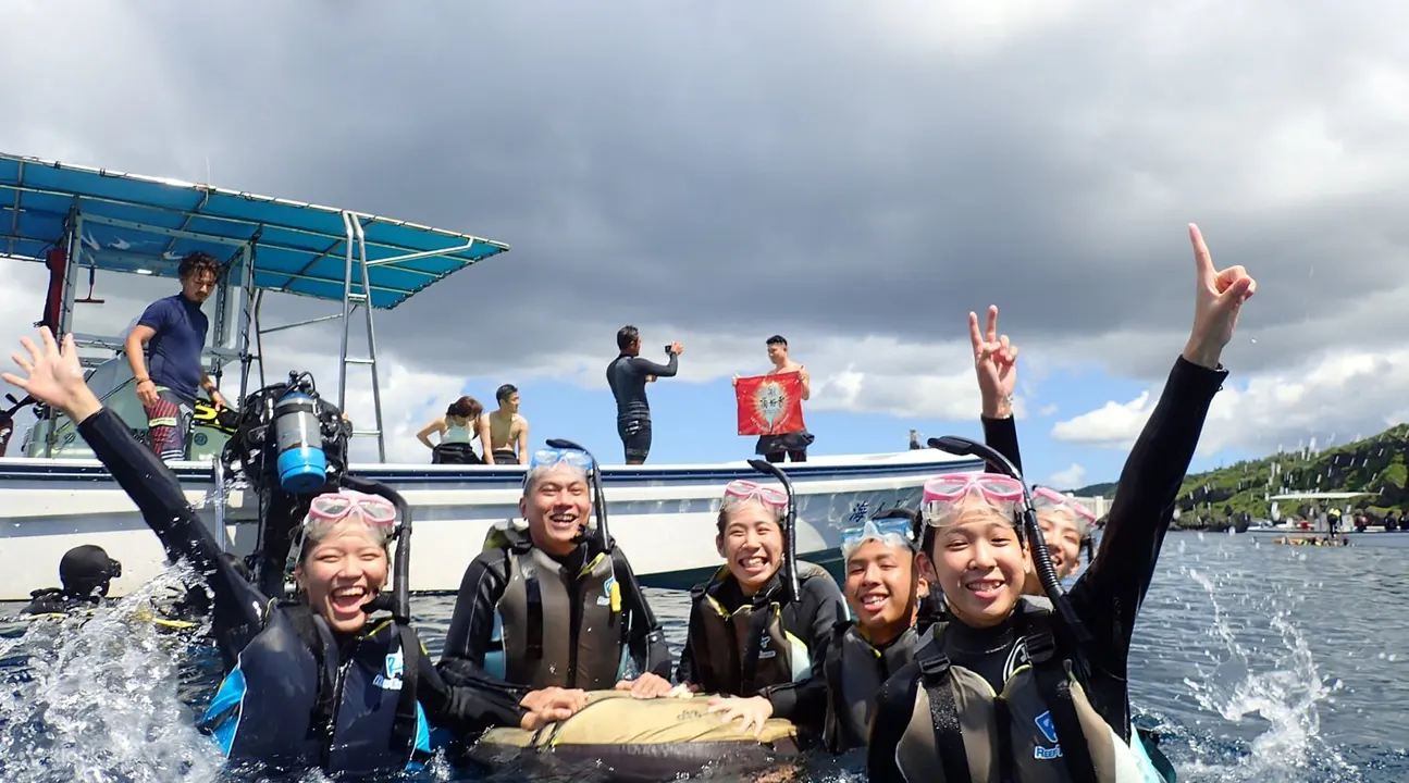冲绳海面上船边的潜水及浮潜者