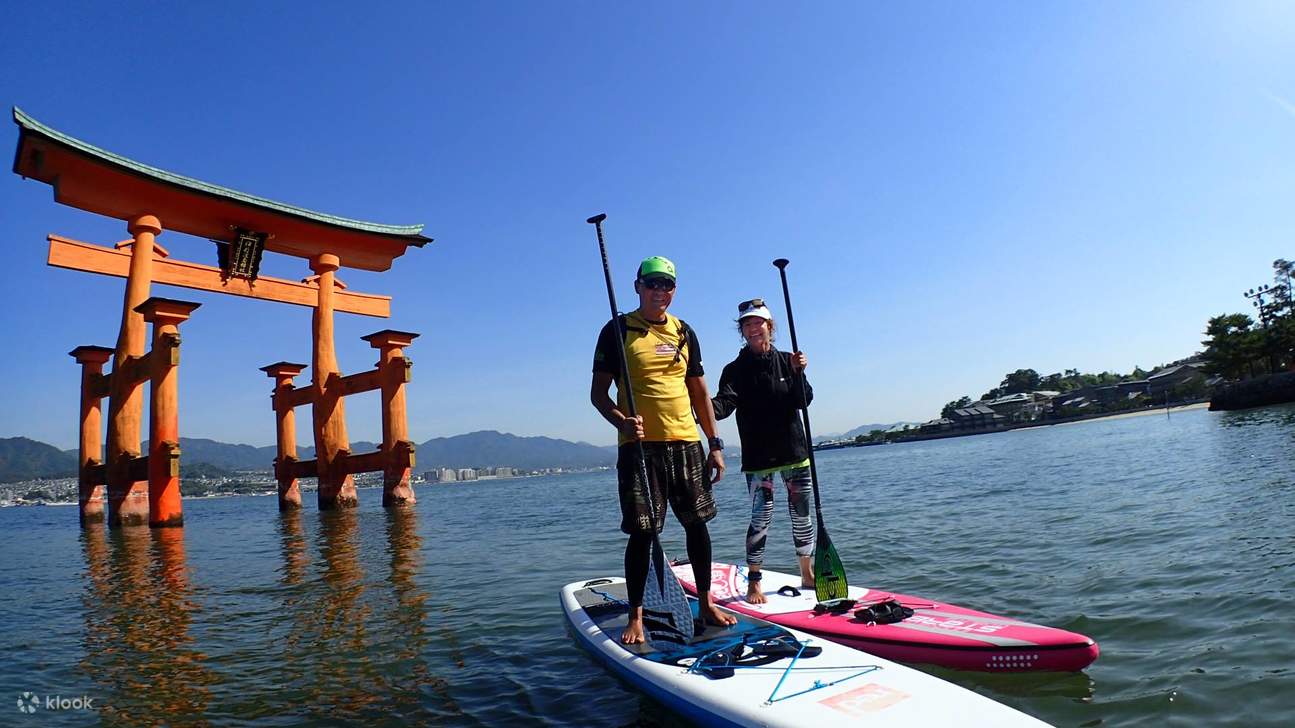 des gens font du paddleboard au sanctuaire d'itsukushima