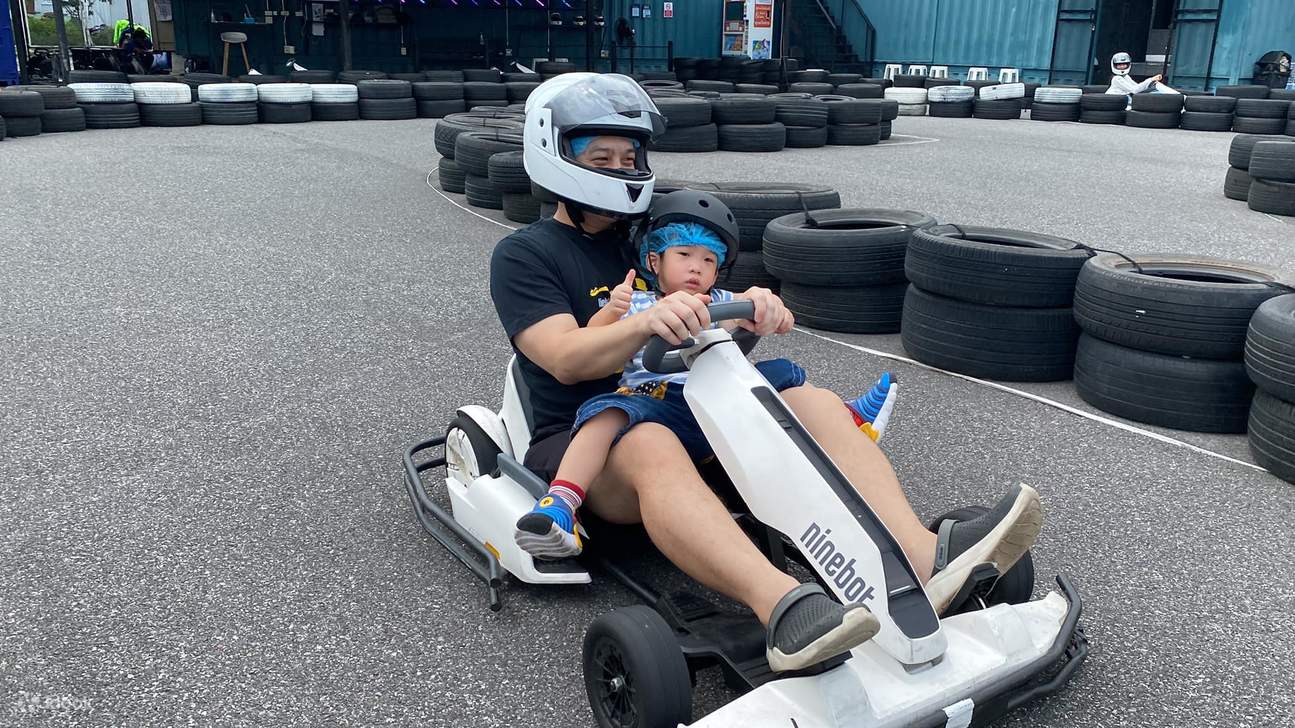 Ein Mann fährt mit seinem Kind Gokart.