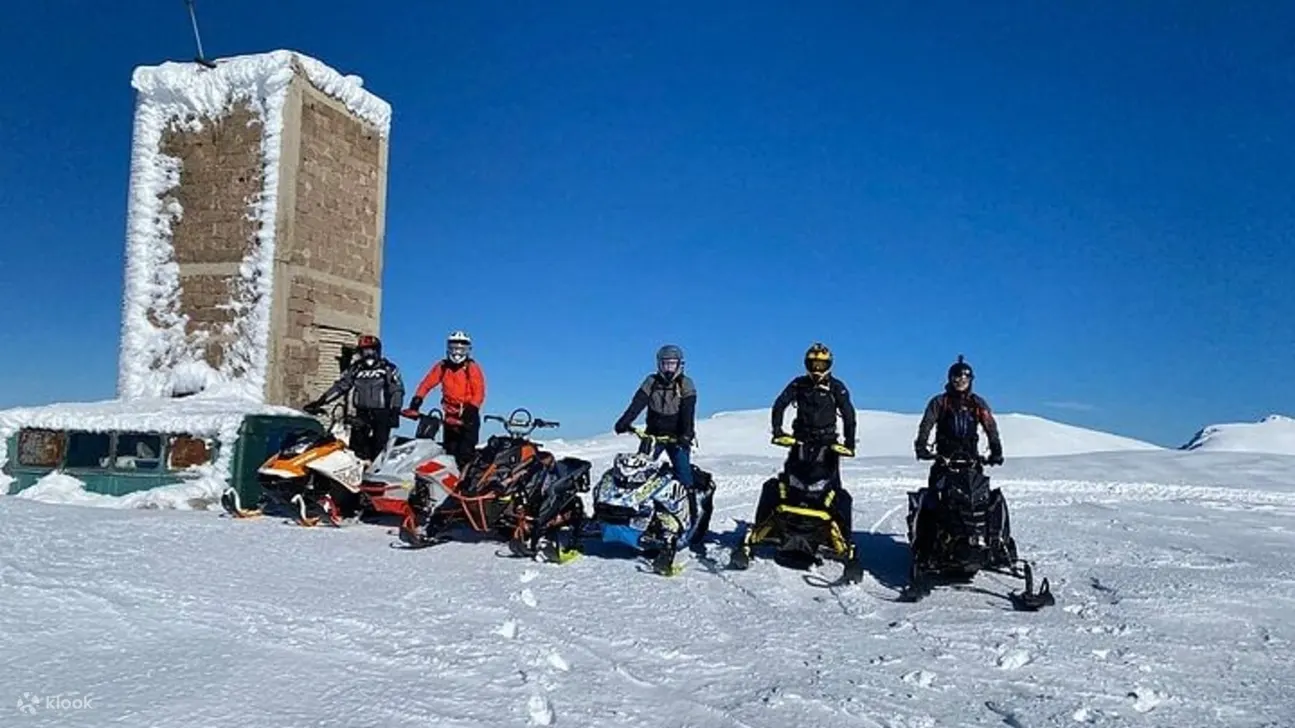 一群兴高采烈的人骑着雪地摩托拍照，周围到处都是新鲜的、未被触碰过的雪