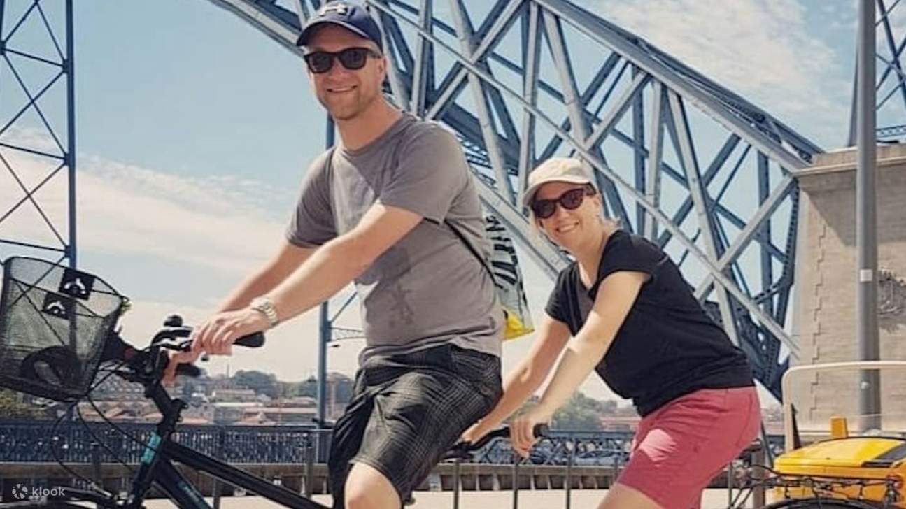 Ciclista paseando con el icónico puente de Oporto bellamente enmarcado en el pintoresco fondo