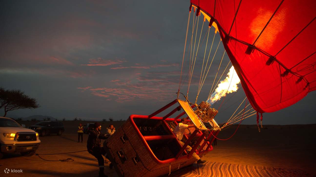 Balon udara panas mengembang saat fajar, bersiap untuk petualangan matahari terbit di gurun yang menakjubkan