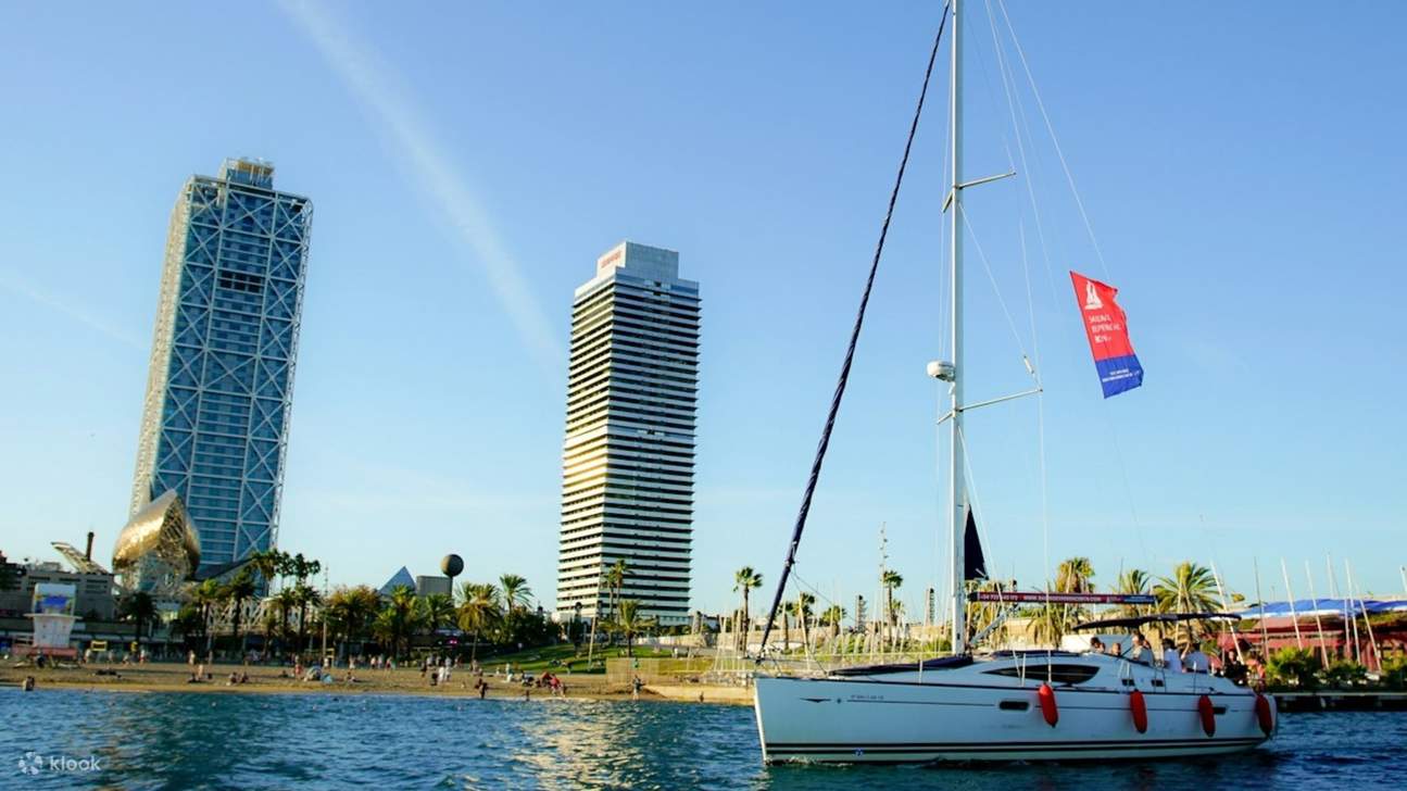 An elegant sailboat glides near the coastline, sunlight dancing on the serene blue water