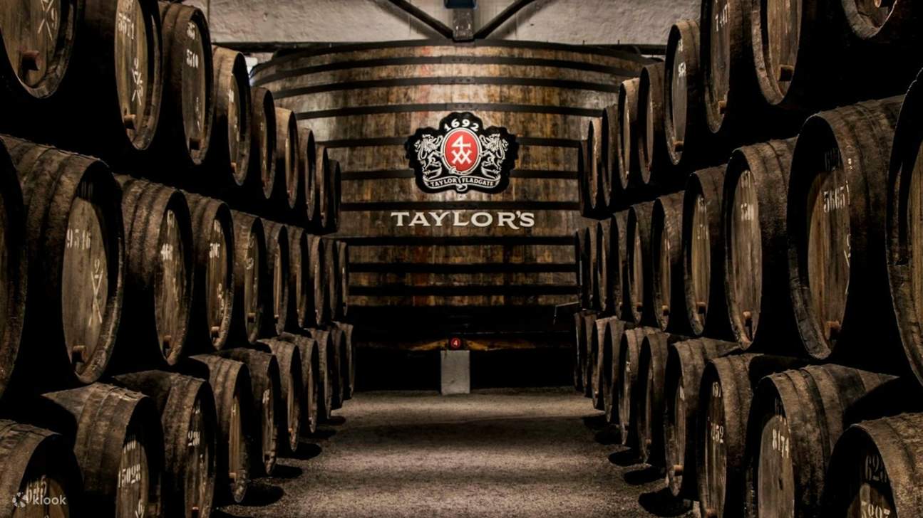 Des barriques de vin en bois bordent un passage de cave faiblement éclairé, évoquant l'histoire et la tradition.
