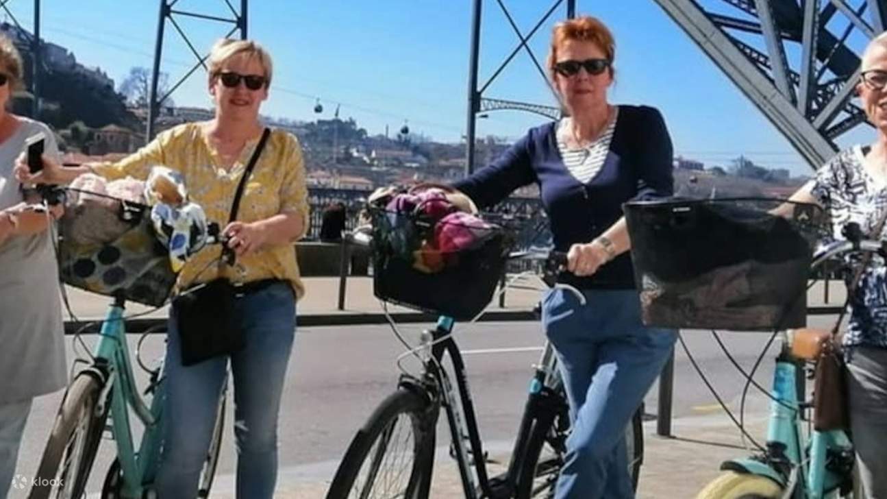 Eine Gruppe von Freunden lacht und fährt gemeinsam Fahrrad und genießt einen sonnigen Tag in Porto.