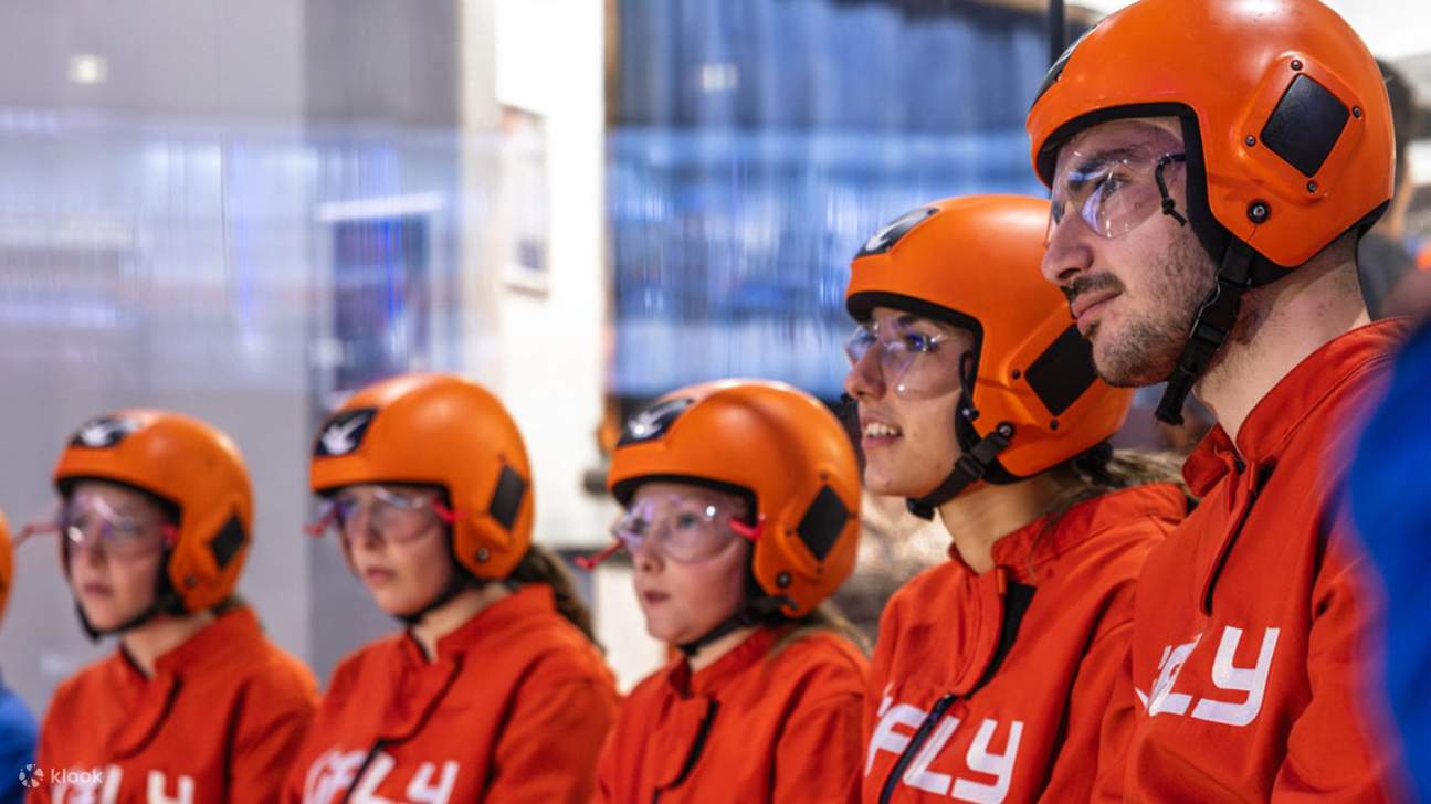 Watch thrill-seekers soar in orange suits, mastering indoor skydiving like true pros