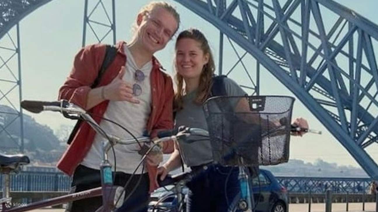 Pareja sonriente posando con sus bicicletas, capturando un momento perfecto cerca del puente