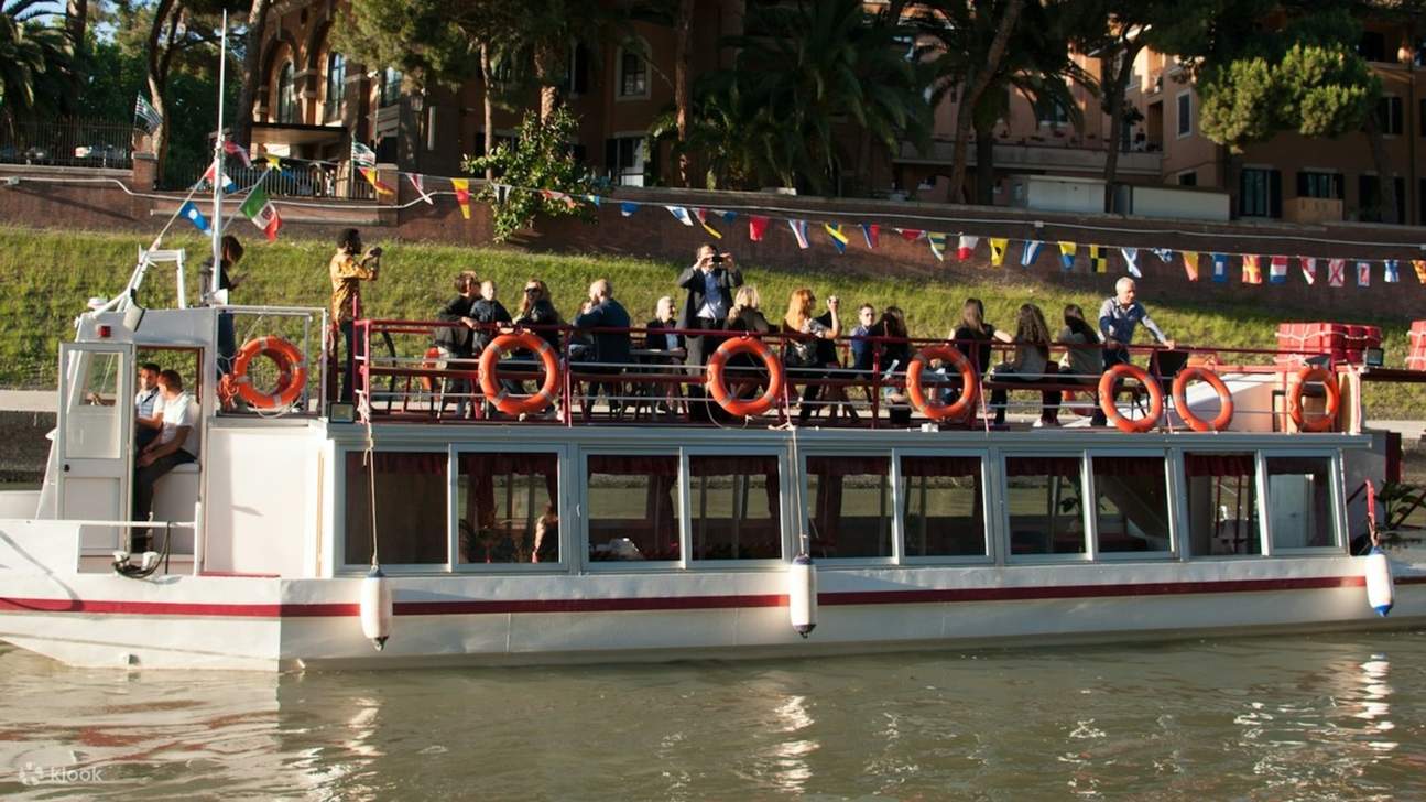 I turisti si rilassano e ammirano le viste panoramiche di Roma a bordo della crociera turistica hop-on hop-off sul Tevere.