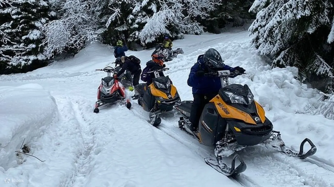 雪地摩托车骑手沿着积雪覆盖的小道上山，享受激动人心的山地探险