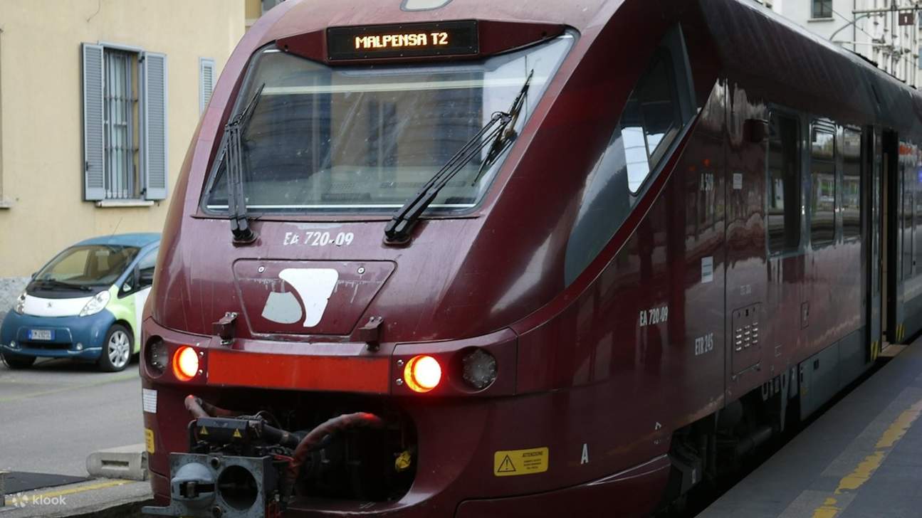 Вид спереди современного красного поезда Malpensa Express на железнодорожных путях