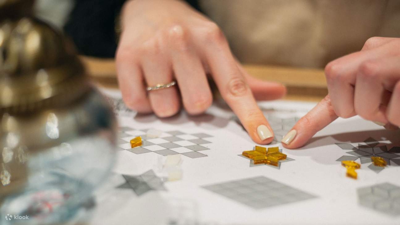 Posizionando con cura pezzi di vetro colorati durante una sessione pratica in un laboratorio di lampade a mosaico di Istanbul