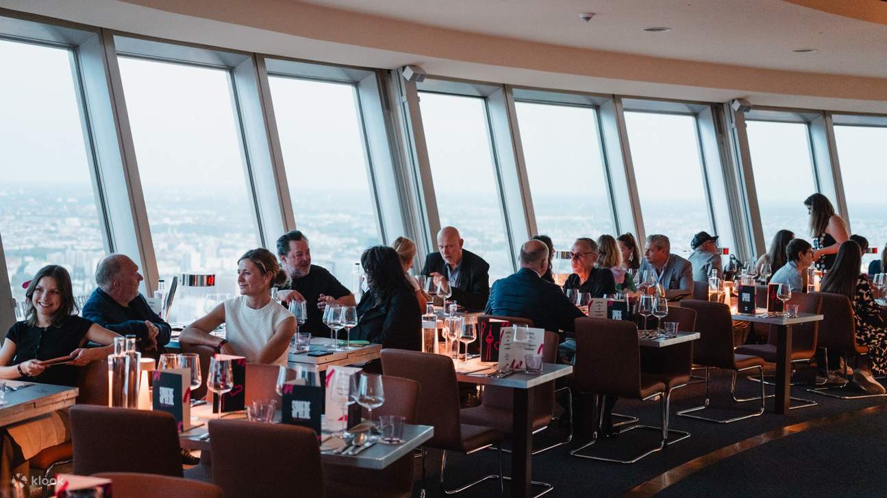 Pengunjung menikmati hidangan di dalam restoran bergaya dengan pemandangan panorama dari menara bandar