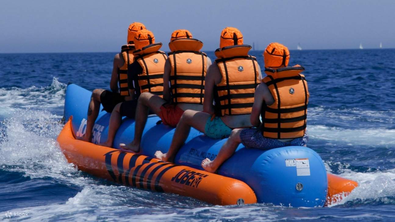 骑手们紧紧抓住香蕉船，香蕉船在海浪中飞驰，到处都是欢笑和浪花