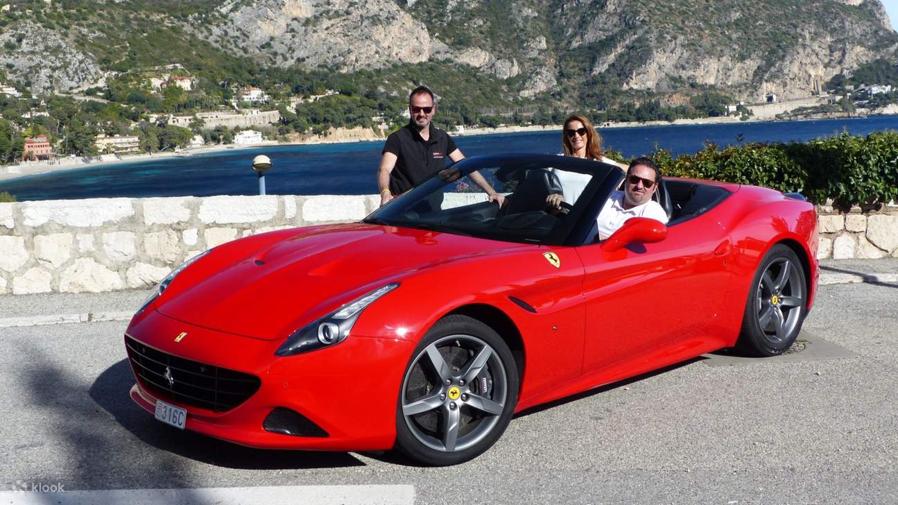 Un passeggero seduto sul sedile posteriore sorride sotto il sole a bordo di una Ferrari California T che sfreccia per Monaco
