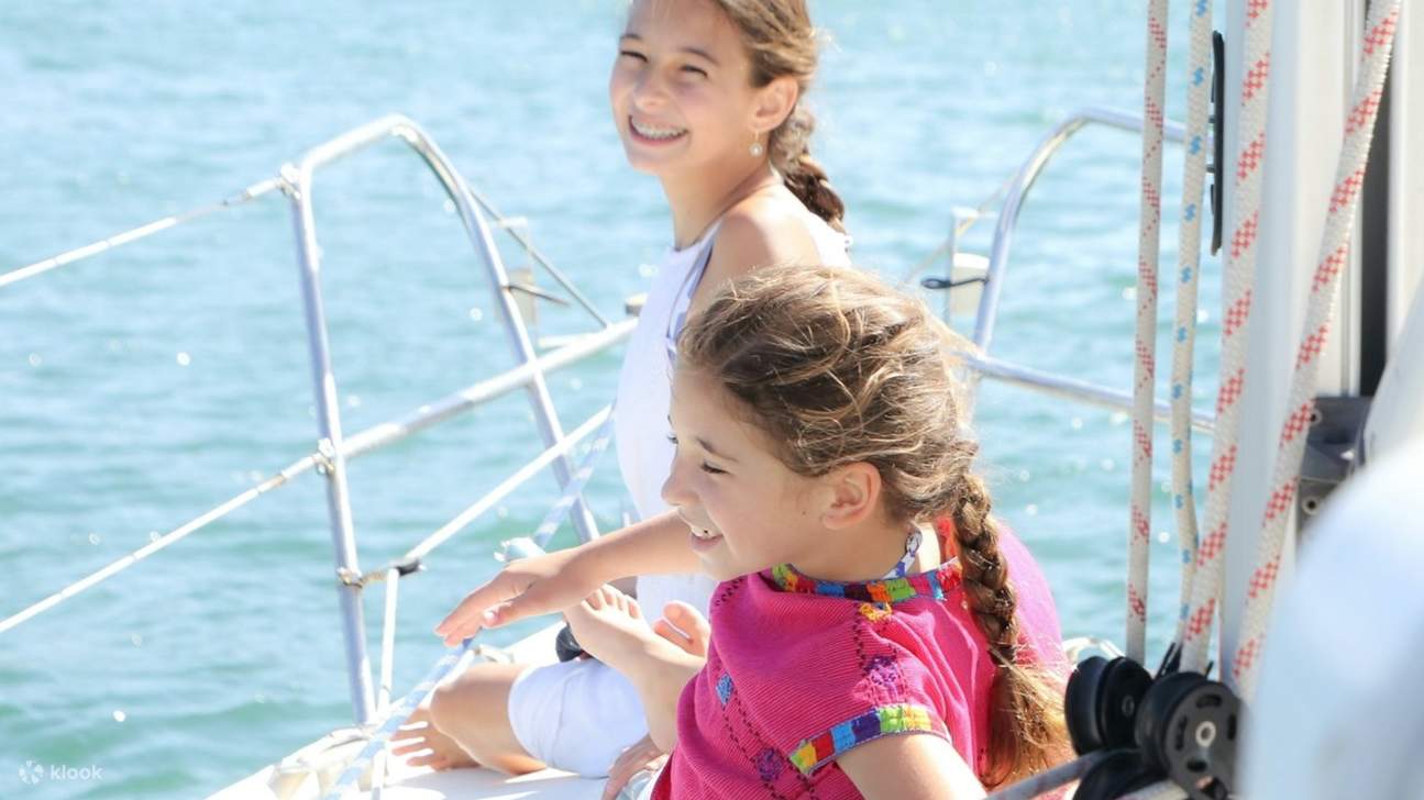 Niños riendo jugando juntos en un barco, la luz del sol bailando en sus rostros alegres.