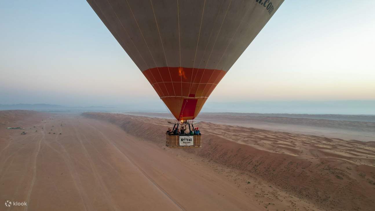 떠오르는 사막의 태양을 배경으로 한 열기구 바구니의 클로즈업 뷰