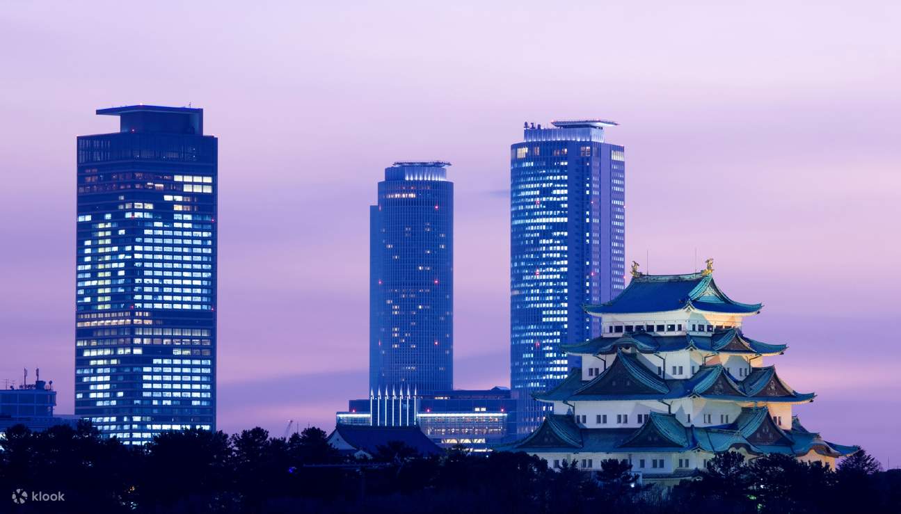 El Castillo de Nagoya iluminado al atardecer con modernos rascacielos en el fondo, mostrando la mezcla de arquitectura tradicional y contemporánea en Nagoya, Japón