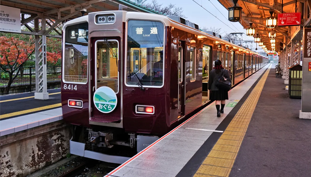 A maroon Hankyu train at a station platform, ready for departure