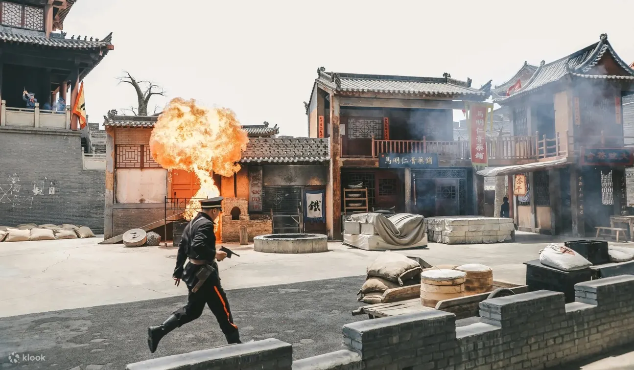 身着民国制服的演员持枪奔走，古建商铺为背景，重现动荡年代的紧张冲突