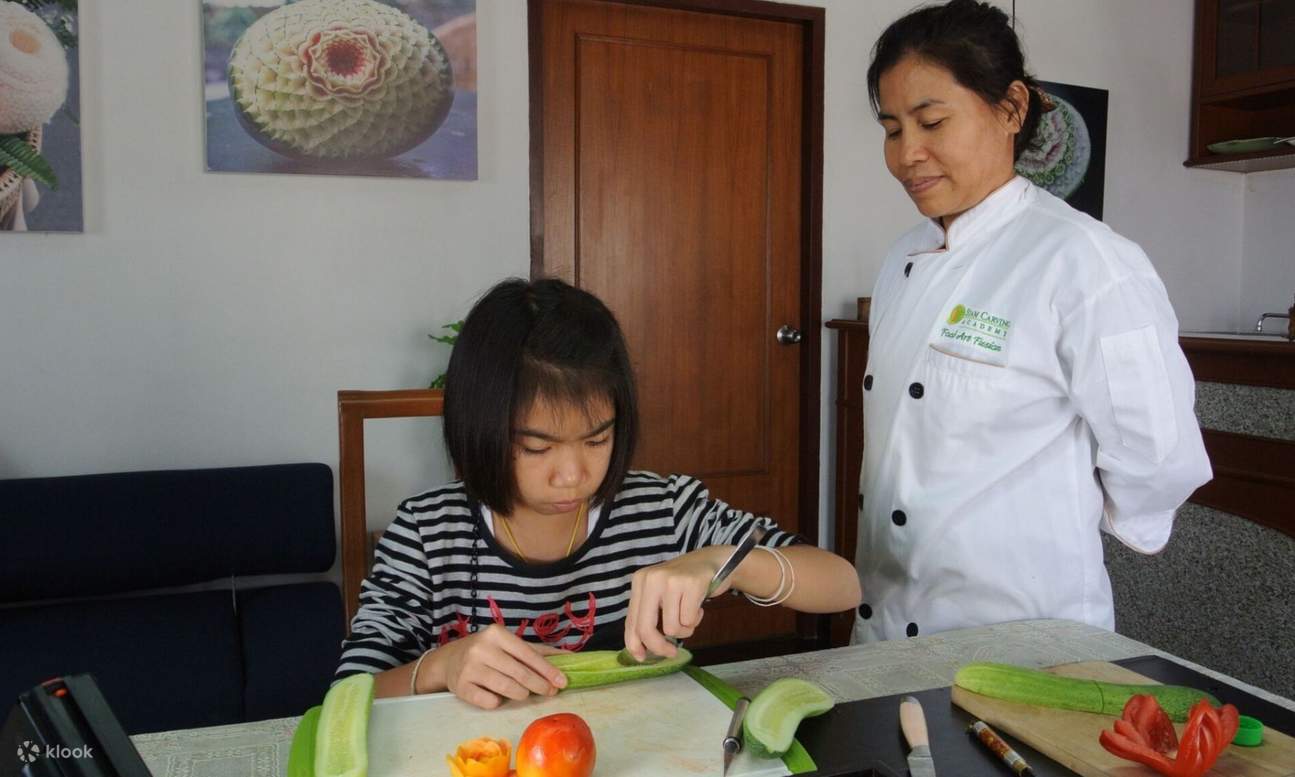 태국 조각가의 지도를 받으며 오이를 조각하는 아이
